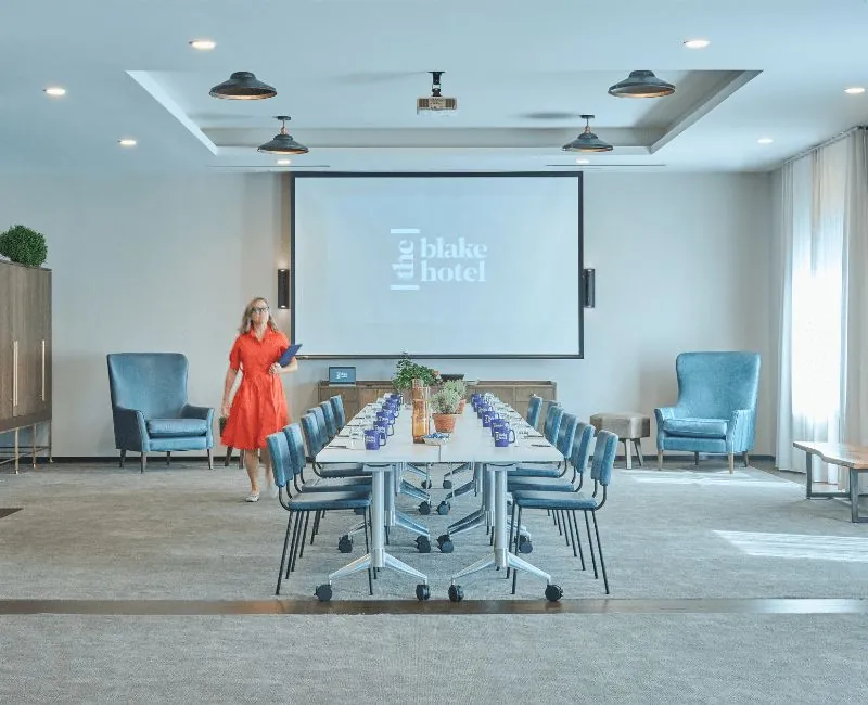 woman in a corporate meeting room with chairs, tables and screen